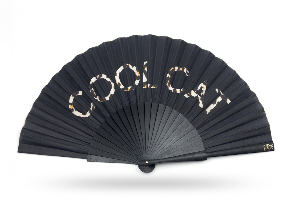 KHU KHU COOL CAT STATEMENT hand-fan with the words cool cat filled with leopard print on a black background. mounted with black wooden sticks and high grade cotton. 